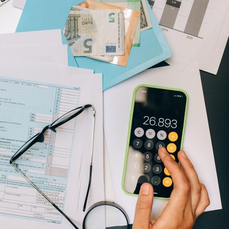 A top view of financial documents, calculator on smartphone, and euro notes, depicting business analysis.